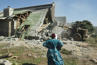 Woman watches as a house is demolished in the clampdown of illegal structures (file photo).