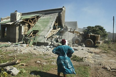 Woman watches as a house is demolished (file photo).