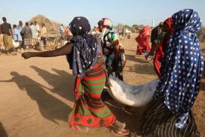 Displaced women carry a sack of food during a UN World Food Programme distribution in Jowhar, Somalia, September 2007.