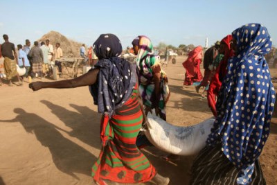 Displaced women carry a sack of food during a UN World Food Programme distribution in Jowhar, Somalia, September 2007. During the holy month of Ramadan, food prices have gone up in Somalia.