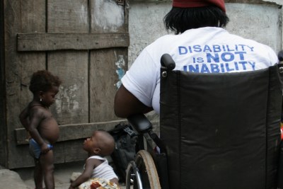 A young woman disabled by polio, her t-shirt reads: 'Disability is NOT inability'. Freetown, Sierra Leone.