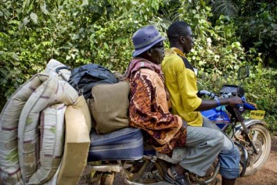 An Ivorian refugee gets a lift on a motorbike taxi to Zwedru,southeastern Liberia.
