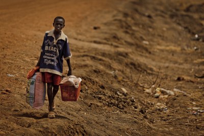 A boy carries his belongings as he flees Abyei.