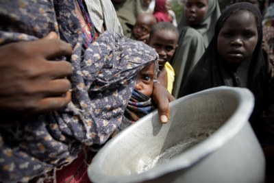 File photo: A woman holding her young malnourished baby queues for food.
