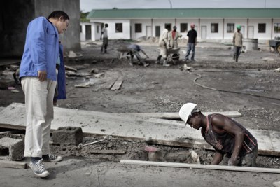 Un ouvrier zambien effectue des travaux de construction à la China Luanshya Mine sous le regard dun directeur chinois.
