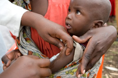 A staff member of the United Nations Children's Fund (UNICEF) vaccinates a child against measles in a refugee camp.