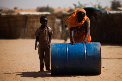 A woman with her child pushes a tank to collect water.