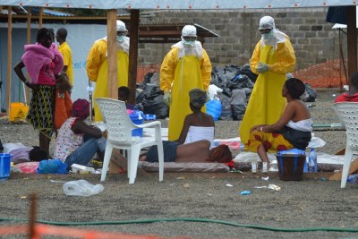 CDC Director Dr. Tom Frieden (in the middle), dressed in Personal Protective Equipment (PPE), talks to patients confirmed to have Ebola at a treatment center operated by Medecins sans Frontieres at ELWA Hospital in Monrovia.