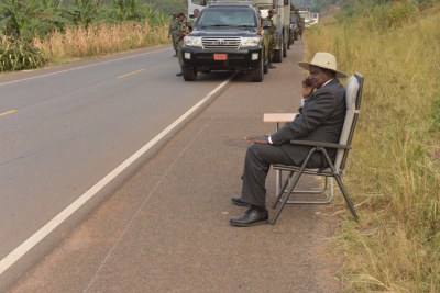 Museveni talking on the phone by the roadside.