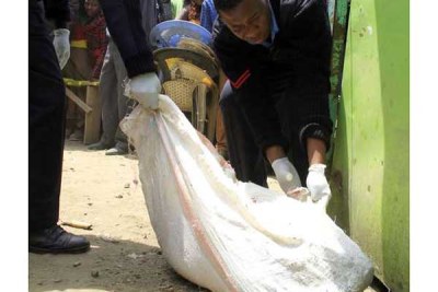 Police officers carry a sack containing a woman's torso that was found in Kayole, Nairobi County.