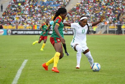 Nigerian player battles for ball against Cameroonian defender.