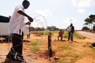 Ejection. Volunteers remove barbed wires which Mr Latimer Mpagi had erected around the contested land.