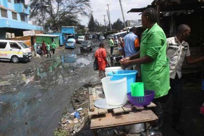 A food vendor goes about her business as raw sewage flows nearby.