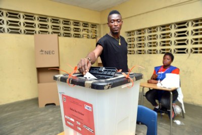A voter puts his ballot in the ballot box during the second round of the presidential election on December 26, 2017