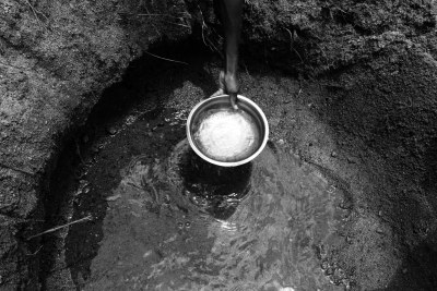 Albertina, 10, scoops water from a hole dug in the dry Lurio riverbed, in M’mele village in Mozambique.