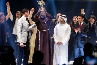 This handout picture provided on March 24, 2019 by the Global Education and Skills Forum, an initiative of the Varkey Foundation, shows Kenyan teacher Peter Tabichi (centre) holding up the Global Teacher Prize (GTP) trophy after winning the U.S.$1 million award during an official ceremony in Dubai presented by Australian actor Hugh Jackman (centre-left) and attended by the Dubai Crown Prince Hamdan bin Mohammed Al-Maktoum (centre-right).