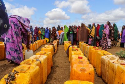 Newly displaced women queue to collect water